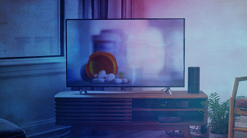 A TV on a media console with a pharmaceutical advertisement on the screen
