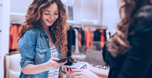 Young woman looking at phone while out shopping with purchases in hand